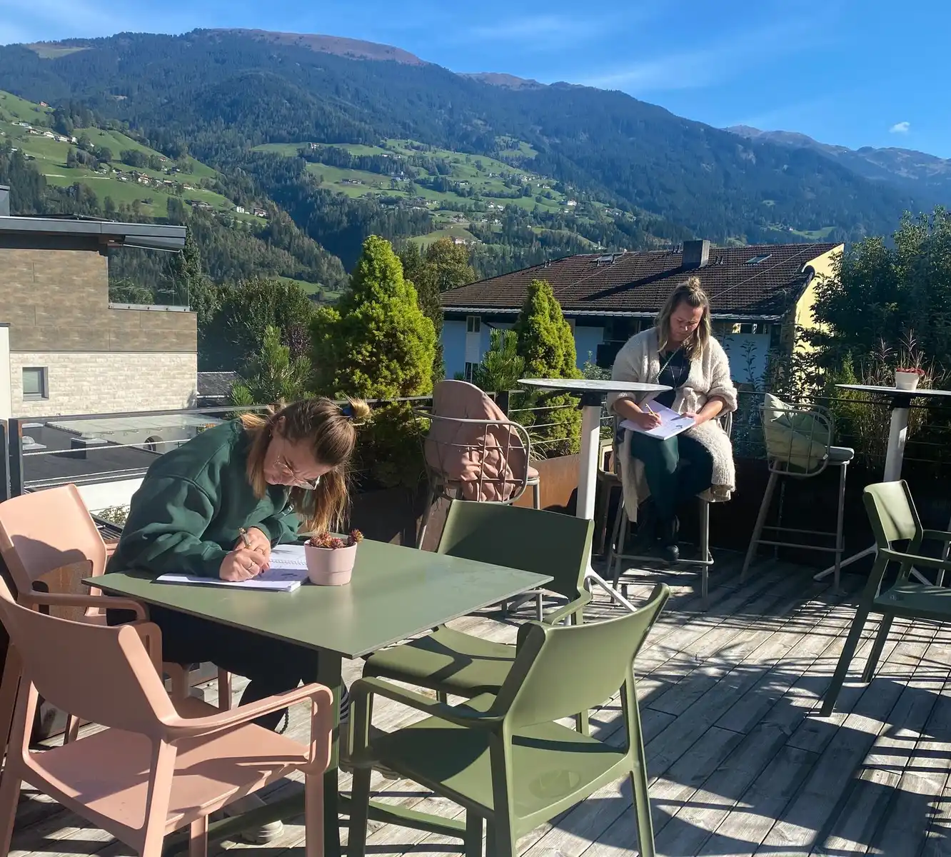 Teilnehmer eines Resilienztrainings arbeiten konzentriert mit Workbook auf einer Dachterrasse
